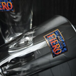 Op de afbeelding: Twee heldere glazen drinkglazen met het woord "FIERO MARTINI" gedrukt op de zijkant van een glas.