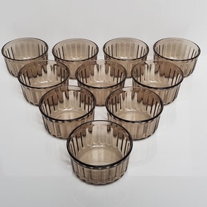 Puede incluir: Conjunto de diez ramequines de vidrio marrón con un diseño acanalado. Los ramequines están dispuestos en forma de triángulo.