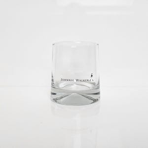 Peut inclure: Un verre &agrave; whisky transparent et cylindrique avec une base &eacute;paisse. Le verre porte le logo "Johnnie Walker" en lettres noires et une silhouette du Striding Man. Id&eacute;al pour servir du whisky ou d'autres spiritueux.