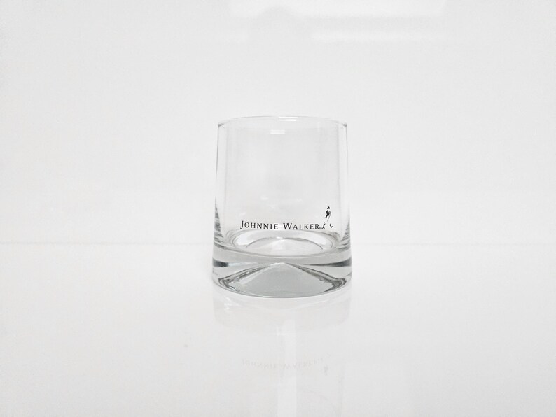 Peut inclure: Un verre &agrave; whisky transparent et cylindrique avec une base &eacute;paisse. Le verre porte le logo "Johnnie Walker" en lettres noires et une silhouette du Striding Man. Id&eacute;al pour servir du whisky ou d'autres spiritueux.