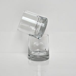 Peut inclure: Deux verres &agrave; whisky transparents empil&eacute;s. Les verres ont une forme arrondie et pr&eacute;sentent le logo "JOHNNIE WALKER" en noir. Les verres sont sur fond blanc.