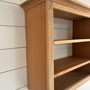 K&ouml;nnte beinhalten: Ein Wandregal aus Holz mit zwei Ablagen. Das Regal ist aus hellbraunem Holz mit einer nat&uuml;rlichen Oberfl&auml;che. Das Regal hat ein schlichtes Design mit einer leicht abgerundeten Oberkante.