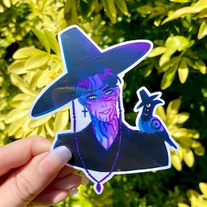 Puede incluir: Una pegatina con una ilustración estilizada de una persona con piel azul y morada, que lleva un sombrero y un atuendo negros. Un pequeño pájaro azul está posado en el hombro de la persona. La persona tiene un pendiente de cruz y un collar con un colgante.