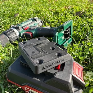 Könnte beinhalten: Ein schwarzer und grüner Akku-Bohrschrauber mit einem schwarzen Akku und einem schwarzen Ladeständer. Der Bohrschrauber hat einen roten Auslöser und der Akku hat den Text "X20V TEAM" aufgedruckt. Der Ladeständer hat den Text "PARKSIDE" aufgedruckt.