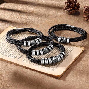 May include: Three black leather bracelets with silver beads. Each bead has a name engraved on it. The names are Palmer, Eaton, Adam, and others.