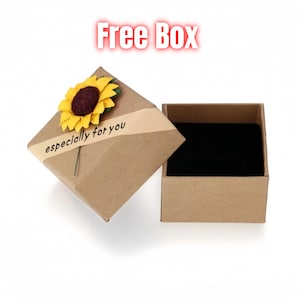 Pu&ograve; includere: Una scatola regalo marrone con una decorazione a girasole e la scritta "especially for you" su un nastro. La scatola &egrave; aperta, rivelando un interno in velluto nero. Il testo "Free Box" &egrave; in alto.