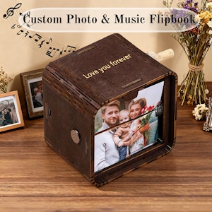 以下が含まれることがあります： 家族写真が見える、濃い茶色の木製フリップブック。フリップブックの上部には「Love you forever」の文字が刻まれています。音符と「Custom Photo & Music Flipbook」の文字も表示されています。