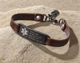 Puede incluir: Una pulsera médica de cuero marrón con una placa de metal oscuro. La placa tiene un símbolo médico y el texto grabado: Tammy Chase, ICE Sylvi 504-1108, Steve 380-4917, No BP/draw right arm.