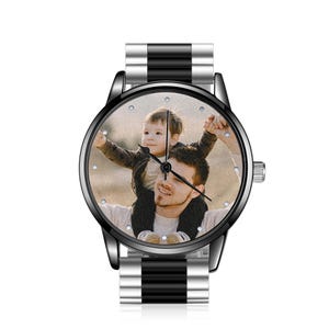 May include: A wristwatch featuring a custom photo dial showing a person carrying a child on their shoulders. The watch has a round black case, a black and silver metal link band, and simple hour markers around the edge of the watch face.