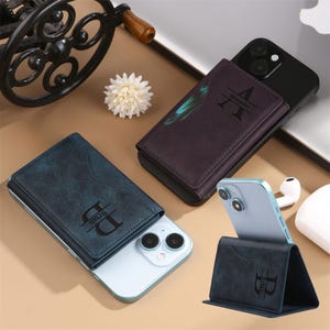 May include: Two phone cases with wallet attachments. The cases are blue and purple with a textured finish. The wallets have a personalized monogram with the letters "B" and "A".