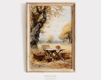 May include: A vintage watercolor painting of a picnic scene in a forest. A wooden table with a white tablecloth is set with a plate and a basket of apples. Two chairs are placed next to the table. The scene is surrounded by trees with yellow and orange leaves. The painting is framed in a white frame.