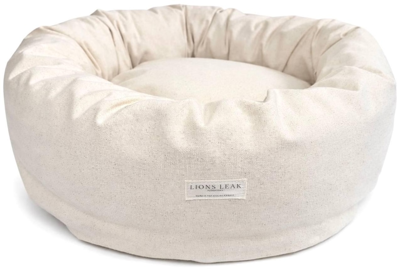 Organic cotton round dog bed in natural beige color with supportive raw cotton filling, removable washable cover, and minimalist donut design.