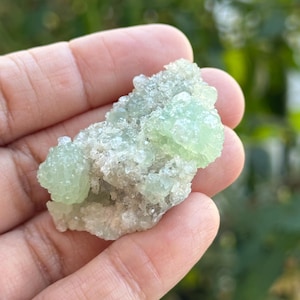 May include: A cluster of green and white calcite crystals. The crystals are small and have a rough, textured surface.