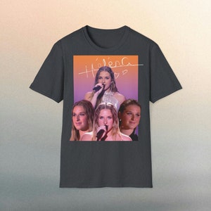Peut inclure: T-shirt gris foncé avec un collage d'une chanteuse, portant le nom "Helena" en écriture cursive. Le design comprend plusieurs images de la chanteuse, sur un fond dégradé orange et violet.