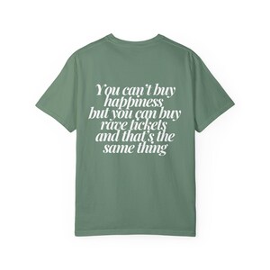May include: A green t-shirt with a white graphic print that reads "You can't buy happiness, but you can buy rave tickets and that's the same thing."