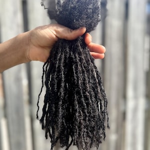 Puede incluir: Un paquete de rastas de cabello humano negro.