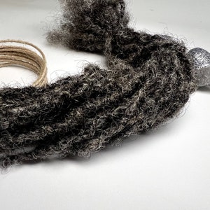May include: A bundle of dark gray and black synthetic dreadlocks.