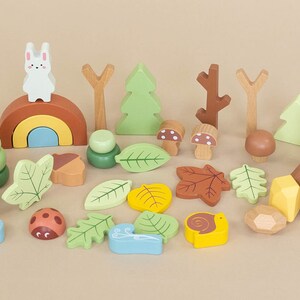 Pode incluir: Um conjunto de blocos de madeira de brinquedo com uma variedade de criaturas da floresta e formas com tema da natureza, incluindo um coelho, um urso, cogumelos, folhas, bolotas e um arco-&iacute;ris. Os blocos s&atilde;o pintados em cores suaves e pastel e s&atilde;o perfeitos para o jogo imaginativo.