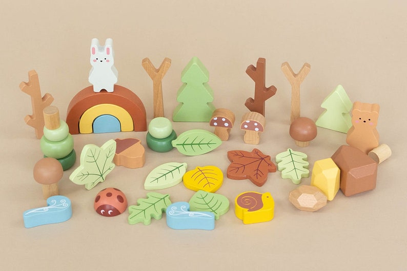 Pode incluir: Um conjunto de blocos de madeira de brinquedo com uma variedade de criaturas da floresta e formas com tema da natureza, incluindo um coelho, um urso, cogumelos, folhas, bolotas e um arco-&iacute;ris. Os blocos s&atilde;o pintados em cores suaves e pastel e s&atilde;o perfeitos para o jogo imaginativo.