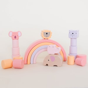 May include: A rainbow-colored wooden arch with a pink, orange, and purple design.  The arch is made up of five pieces that can be stacked on top of each other.  There are also several wooden animal figures, including a koala, a lion, a hippo, and an elephant.  The animals are all painted in pastel colors.