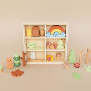 Pode incluir: Uma caixa de madeira com uma variedade de brinquedos de madeira coloridos, incluindo um arco-&iacute;ris, cogumelos, &aacute;rvores, folhas e animais. A caixa tem nove compartimentos e &eacute; perfeita para guardar e organizar brinquedos pequenos.