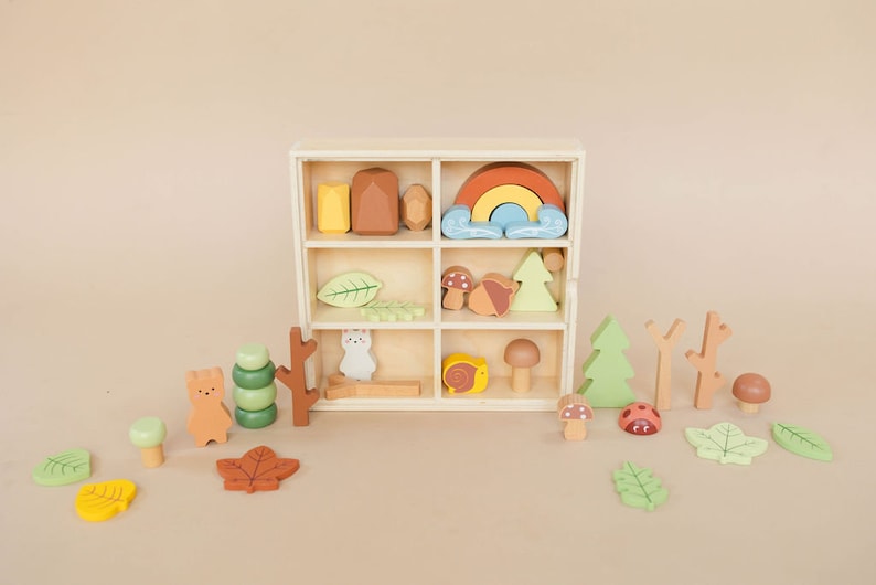 Pode incluir: Uma caixa de madeira com uma variedade de brinquedos de madeira coloridos, incluindo um arco-&iacute;ris, cogumelos, &aacute;rvores, folhas e animais. A caixa tem nove compartimentos e &eacute; perfeita para guardar e organizar brinquedos pequenos.