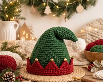 May include: A crocheted elf hat featuring a dark green pointed crown, a white pom-pom at the tip, and a red scalloped brim adorned with small gold jingle bells. The hat is constructed with a textured yarn stitch and sits on a round woven mat.
