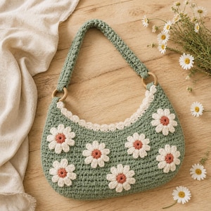 May include: A sage green crochet handbag featuring a crescent shape and a single handle attached with wooden rings. The bag is decorated with several white daisy appliques with orange centers and finished with a scalloped cream-colored trim.
