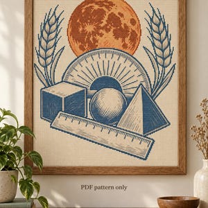 May include: A framed cross-stitch embroidery featuring a large orange moon above a blue geometric arrangement of a cube, a sphere, a pyramid, a protractor, and a ruler, flanked by two stalks of wheat. The text "PDF pattern only" is printed below.