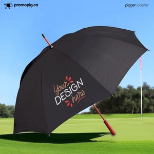 May include: Black golf umbrella with a wooden handle and the text "Your DESIGN here" in white and red. The umbrella is open on a green golf course with a blue sky in the background.