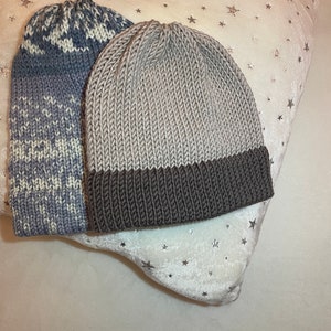 K&ouml;nnte beinhalten: Zwei Strickm&uuml;tzen, eine graue mit braunem Rand und eine blau-wei&szlig; gemusterte M&uuml;tze.