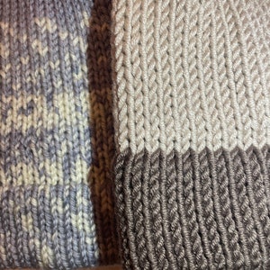 K&ouml;nnte beinhalten: Zwei Strickm&uuml;tzen, eine mit einem grau-wei&szlig;en Ombre-Muster und die andere mit einem beige-braunen Farbblockmuster.