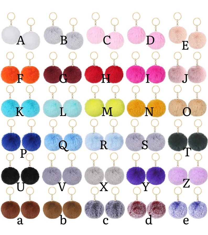 May include: Assortment of 26 colorful fluffy pom pom keychains with gold key rings. The pom poms are arranged in alphabetical order from A to E, F to J, K to O, P to T, U to Z, and a to e.