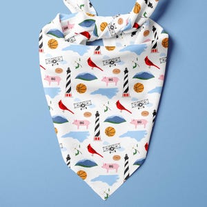 May include: White bandana with a repeating pattern of a basketball, red cardinal, airplane, lighthouse, pig, and mountain. The bandana is tied at the top with two knots.