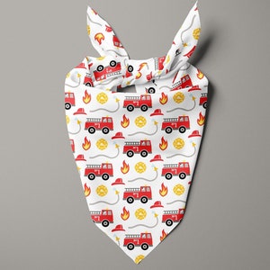 May include: White bandana with a repeating pattern of red fire trucks, yellow flames, fire hats, and fire department emblems. The bandana is tied at the top. The design is playful and suitable for pets.