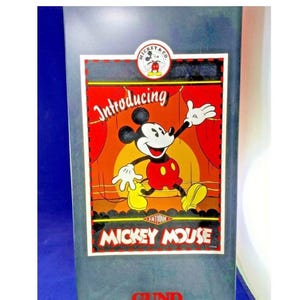 May include: A vintage Mickey Mouse advertisement on a gray background. The image features Mickey Mouse in a red and yellow outfit, with the words "Introducing" and "Mickey Mouse" prominently displayed. The logo "Mickey & Co." is at the top.