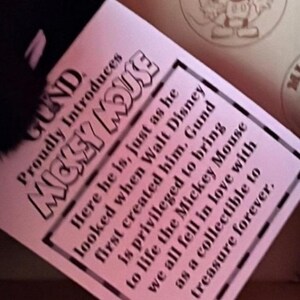 May include: A pink tag with black text introduces "Mickey Mouse" by Gund. The tag includes text about the character's creation and the brand's privilege in bringing Mickey Mouse to life as a collectible.