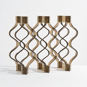 May include: Three brown, wavy, decorative panels with a repeating diamond pattern. The panels are made of a translucent material and stand upright on a white surface. The design is modern and geometric.