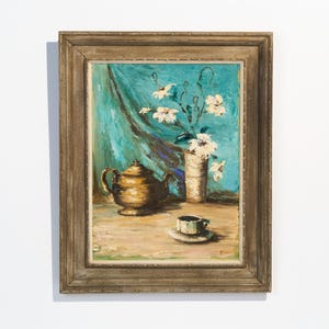 May include: Oil painting in a wooden frame depicting a still life. A golden teapot, a cup and saucer, and a vase of white flowers are arranged on a table against a teal backdrop. The artwork has a vintage aesthetic.
