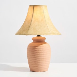 Puede incluir: Una base de lámpara de terracota con un diseño texturizado y ondulado y una pantalla de color crema.
