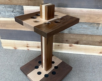 May include: A wooden pool cue rack with a square base and a round top. The rack is made of walnut and maple wood and has a two-tone design. The base has a circular pattern of holes for storing pool cues.