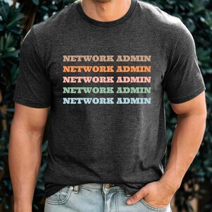 May include: A dark heather grey t-shirt with the text "NETWORK ADMIN" repeated five times in different pastel colours.