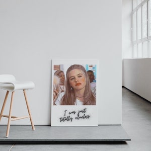 Op de afbeelding: Een witte ingelijste print met een foto van een jonge vrouw met lang blond haar. De foto is in een Polaroid-stijl frame met de tekst "I was just totally clueless" gedrukt onder de foto.