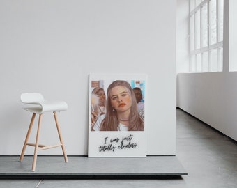 Op de afbeelding: Een witte ingelijste print met een foto van een jonge vrouw met lang blond haar. De foto is in een Polaroid-stijl frame met de tekst "I was just totally clueless" gedrukt onder de foto.