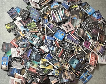 May include: A collection of miniature books with various titles and cover designs. The books are scattered across a surface, showcasing a variety of colors and fonts. Titles include "The Girl Manor", "Witness", and "Saving Noah".