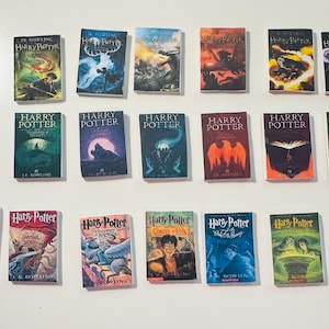 May include: A collection of 15 miniature Harry Potter books, each featuring a different cover art from the series. The books are arranged in three rows of five, with the spines facing the viewer. The covers feature various characters, creatures, and scenes from the books, including Harry Potter, Ron Weasley, Hermione Granger, Dumbledore, Voldemort, and the Hogwarts Express.