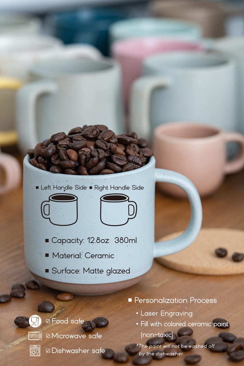 May include: A light blue ceramic mug with a matte glaze and a 12.8 ounce capacity. The mug has a handle on the right side and features a black outline of a mug on each side. The mug is filled with coffee beans and is sitting on a wooden surface. The text on the mug reads "Left Handle Side Right Handle Side" and "Capacity: 12.8oz 380ml". The text below the mug reads "Food safe", "Microwave safe", and "Dishwasher safe". The text on the right side of the mug reads "Personalization Process", "Laser Engraving", and "Fill with colored ceramic paint (non-toxic)".