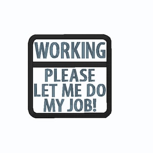 May include: A square sign with a black border and white background. The sign has the words "WORKING" at the top, followed by "PLEASE LET ME DO MY JOB!" in blue text.