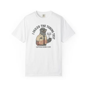 May include: A white short-sleeve t-shirt featuring a graphic of a pigeon wearing glasses, a tie, and a short-sleeve shirt. The text reads I FAILED THE TURING TEST, ARE YOU HUMAN?, REJECTED, and CAPTCHA SCORE: 0.02, with a checkbox graphic.