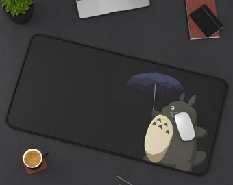 May include: Black mouse pad with a cartoon character holding an umbrella. The character is gray with a white belly and has three eyes. The background is black.